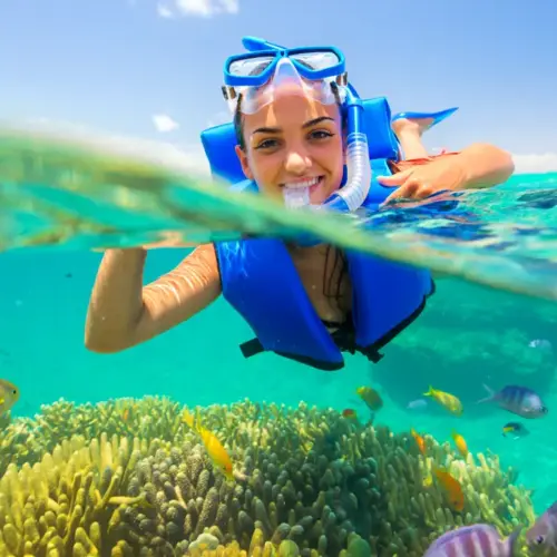 Happy beginner snorkeler floating in clear turquoise water in Puerto Rico with coral visible below.