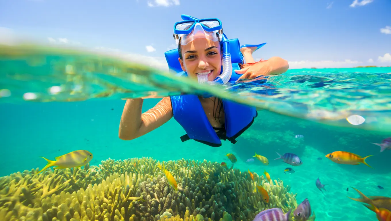 Happy beginner snorkeler floating in clear turquoise water in Puerto Rico with coral visible below.